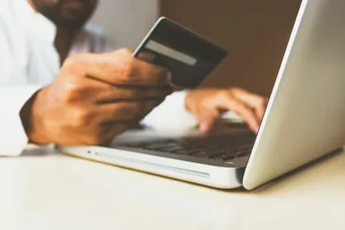 Person paying online with a card on a laptop